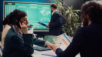 Business manager talking on phone call with the accountant to see the stock market trends progress, calling her associate to obtain more funding for a developing project. Boardroom. Camera B. photo