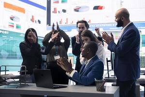 Business administrator celebrating expansion progress with his team, clapping hands in the organizational coworking space. CEO is pleased about new fruitful investment and collaboration. photo