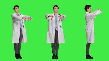 Displeased physician showing thumbs down symbol against greenscreen backdrop, expresses negativity and rejection. Doctor feeling dissatisfied and disagreeing with an idea, dislike sign. Camera A. photo