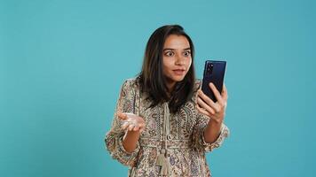 Irked woman fighting with friends during smartphone videocall, isolated over studio background. Outraged person arguing with mates during conversation on mobile phone, camera A photo