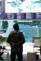 Infantry unit recruit analyzing important battlefield data on big screen, gathering information for future special operations or missions. Military personnel reviewing gps tracking satellite imagery. photo