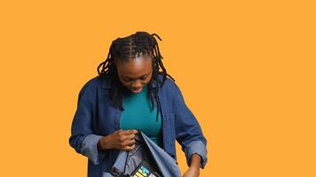 Portrait of happy woman searching through backpack, looking for school materials, studio background. Jolly girl taking out university supplies out of rucksack, preparing for college, camera A photo