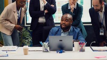 Diverse corporate employees analyzing project updates to ensure goal accomplishment, reviewing infographics on laptop and finding ways to obtain new funds. Business management team. Camera A. photo