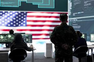 US army official working on ensuring servers protection and state secrets, protecting important hybrid warfare data in high tech agency office. Military soldier supervises hacking activity. photo