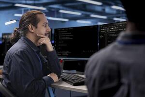 Admin in data center updating systems, protecting hardware equipment from damaging software vulnerabilities. Colleagues looking for bugs causing infrastructure to slow down photo