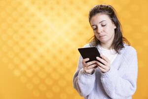Person with sad facial expression reading ebook on ereader, gathering information for school exam in book, fed up with studying, studio background. Student sulking while reading textbook on tablet screen photo