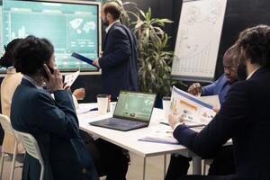 Team leader talking on phone call with the accountant to check stock trends progress, calling her business partner to obtain more funds for a developing project. Boardroom conference. photo