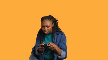 African american gamer holding controller, focused on finishing difficult videogame level. Woman gaming with gamepad, solving quests, isolated over studio backdrop, camera A photo