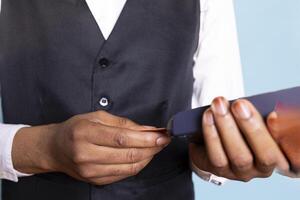 Hotel concierge with suit and tie presenting the card and pos terminal to receive his payment at five star resort. Asking to pay foe lodging, service oriented amenities. Close up. photo