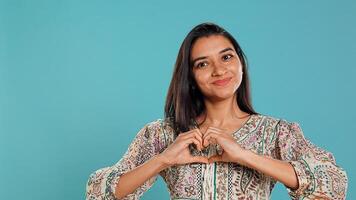 Portrait of jolly friendly indian woman doing heart symbol shape gesture with hands. Cheerful nurturing person showing love gesturing, isolated over studio background, camera B photo