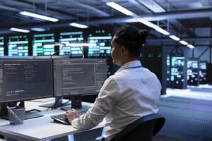 Admin in data center updating systems to keeps performance up and protect servers from easily exploitable software vulnerabilities. Worker looking for errors causing servers to slow down photo