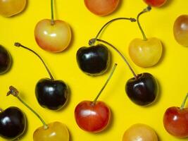 Sweet cherry with a stem on a yellow background. Bright table. Berries on the table. Delicious food. Berries of different colors. photo