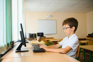 Elementary School Computer Science Classroom, Smart Little Schoolboy Works on Personal Computer photo