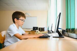 Elementary School Computer Science Classroom, Smart Little Schoolboy Works on Personal Computer photo