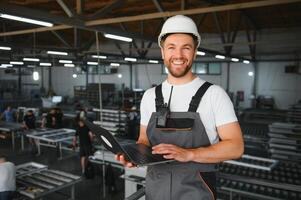 Men industrial engineer wearing a white helmet while standing in a heavy industrial factory behind photo