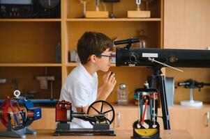 Physics lesson. A student at a desk with scientific instruments and a telescope photo