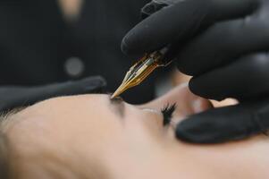 hands of the master who performs the procedure of permanent makeup of eyebrows. Permanent eyebrow makeup PMU for brunettes photo