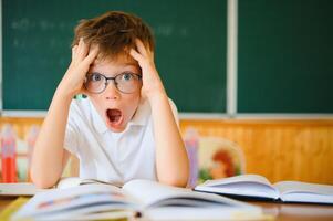 Portrait of a confused or surprised student at a desk in a classroom photo