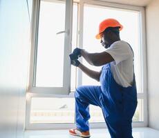 Worker in installing white plastic upvc window on house photo