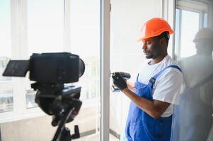 A worker inserts plastic windows and records a on a camera. Builder's blog photo