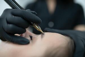 hands of the master who performs the procedure of permanent makeup of eyebrows. Permanent eyebrow makeup PMU for brunettes photo