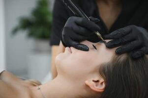 hands of the master who performs the procedure of permanent makeup of eyebrows. Permanent eyebrow makeup PMU for brunettes photo