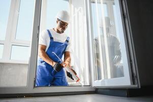 Young Male Worker Applying Silicone Sealant With Silicone Gun photo
