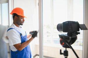 A worker inserts plastic windows and records a on a camera. Builder's blog photo