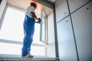 Worker installing plastic window indoors photo
