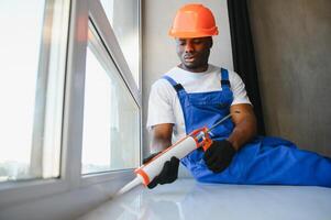 Worker in installing white plastic upvc window on house photo