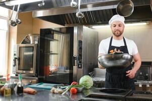 Chef cook in uniform cooking in the big cooker at the restaurant kitchen photo