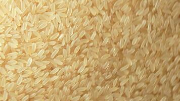 Dry Uncooked Parboiled Rice Background Rotating Clockwise - Top View. Scattered Raw Long Grain Rice. Asian Cuisine and Culture. Healthy Eating Ingredients. Diet Food. Angular Rotation Right video