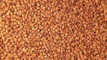 Dry Uncooked Brown Buckwheat Groats, Slowly Rotating Background - Top View. Raw Large Buckwheat Grains. Russian, Ukrainian and Belarusian Culture. Rotation Left video