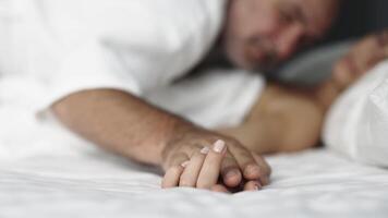 A close-up of a couple's hands intertwined on the bed, capturing a moment of relaxation. This scene conveys the connection and pleasure in their loving relationship video