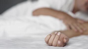 A close-up of a couple's hands intertwined on the bed, capturing a moment of relaxation. This scene conveys the connection and pleasure in their loving relationship video