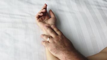 A close-up of a couple's hands intertwined on the bed, capturing a moment of relaxation. This scene conveys the connection and pleasure in their loving relationship video
