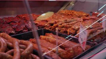 Fresh raw and marinated meat with tags on the showcase in the butchers store. video