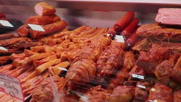 Smoked beef and lamb along with different types of salami in show window. video