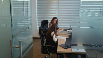Two female coworkers working on project, one shows results the other typing on computer. video