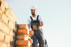 Man bricklayer installing bricks on construction site photo