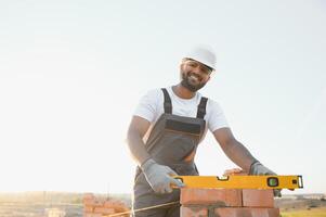 Indian Construction worker man in work clothes and a construction helmet. Portrait of positive male builder in hardhat working at construction site photo