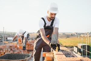 Construction worker man in work clothes and a construction helmet. Portrait of positive male builder in hardhat working at construction site photo