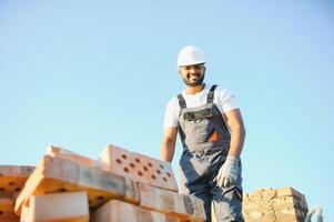Indian Construction worker man in work clothes and a construction helmet. Portrait of positive male builder in hardhat working at construction site photo