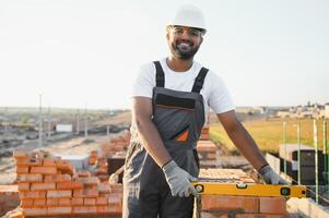 Installing brick wall. Indian Construction worker in uniform and safety equipment have job on building photo