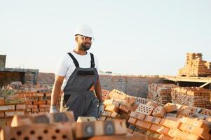 Portrait of an Indian construction worker in overalls and a hard hat at a construction site photo