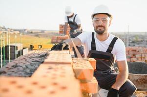 Construction worker man in work clothes and a construction helmet. Portrait of positive male builder in hardhat working at construction site photo