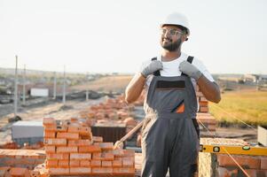 Installing brick wall. Indian Construction worker in uniform and safety equipment have job on building photo