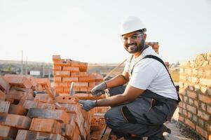Indian Construction worker man in work clothes and a construction helmet. Portrait of positive male builder in hardhat working at construction site photo