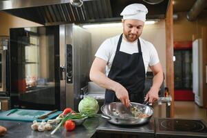 Chef cook in uniform cooking in the big cooker at the restaurant kitchen photo