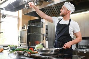 Chef cook in uniform cooking in the big cooker at the restaurant kitchen photo